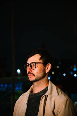 Gece hayatı ve moda anlayışı için renkli ışıkları olan Bogota şehrinde yalnız poz veren genç bir adam. Yüksek kalite fotoğraf
