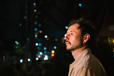 Tek başına genç bir adam gece hayatı konsepti için canlı renkli ışıkları olan Bogota şehrinin canlı gece hayatını izliyor. Yüksek kalite fotoğraf