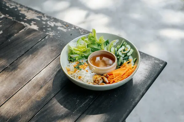 Bir kase taze sebze ve pirinç erişteli salata, sirke soslu, Serene Backyard Morning 'de servis edilmiş.