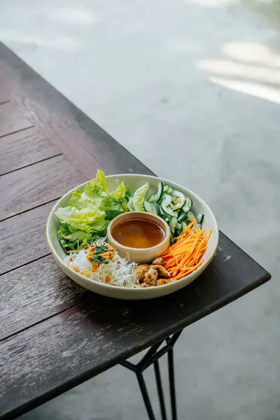 Dilimlenmiş salatalık, havuç, mantar ve pirinç erişteli canlı bir kase taze salata. Arka bahçede serin bir sabahın tadını çıkar.