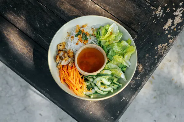 İçinde salatalık, havuç, mantar, marul, pirinç eriştesi ve sirke sosu bulunan bir kase taze ev yapımı salata.