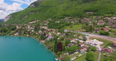 Görkemli dağların arasına yerleştirilmiş turkuaz bir gölün nefes kesici drone görüntüleri. Büyüleyici bir göl kenti bu doğa cenneti manzarasını güzelleştirir. Yaratıcı projeleriniz için çarpıcı 4K stok videoları indirin.