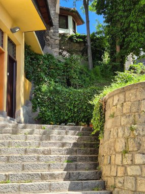 Etrafı yeşilliklerle çevrili taş merdivenlerle iniyor.