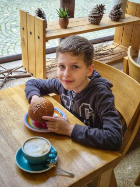 Kakaolu ve çörekli çocuk tahta bir masada oturuyor.