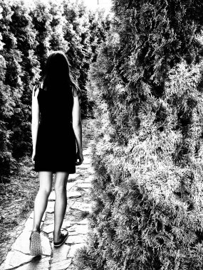 Genç bir kadın eşkıyalar arasında taş bir patika boyunca yürüyor. Esmer, dikiz aynasından. siyah beyaz fotoğraf