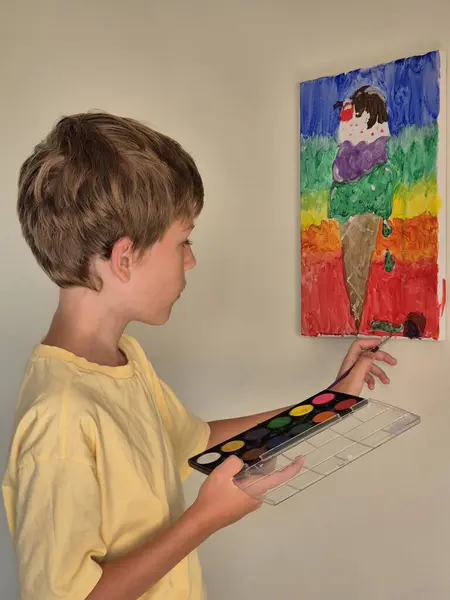 Çocuk tuval üzerine bir resim çiziyor. Genç ressam bir resim çiziyor..