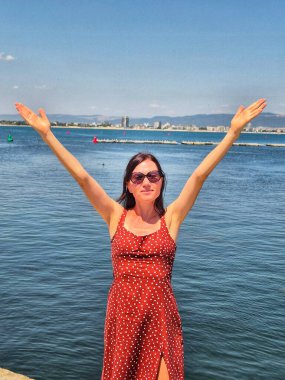 Denizin kenarında elleri havada bir kadın. Mutlu kadın tatilde..