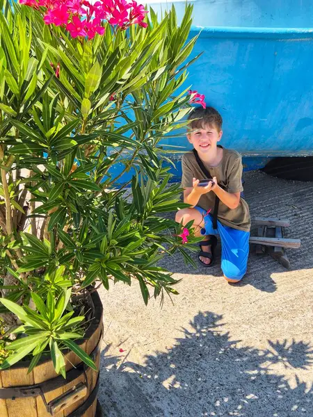 Bir çocuk sahildeki küçük bir teknenin yanında akıllı telefon kullanıyor..