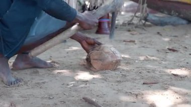 Afrikalı adam baltayla hindistan cevizi kırıyor.