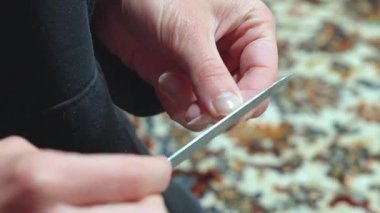 Kadının elleri halıya tırnaklarını törpülüyor.