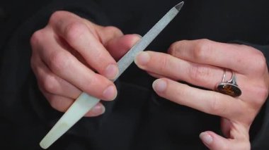 Kadının elleri tırnaklarını törpülüyor. 