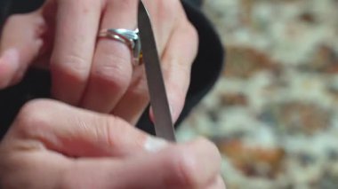 Kadının elleri halıya tırnaklarını törpülüyor.