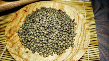 Ahşap kasede ahşap mercimek, suşi hasırı ve tahta kesme tahtası arka planda yüksek açılı.