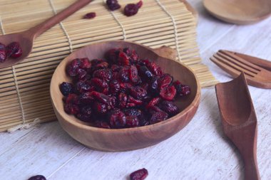 Kurutulmuş kırmızı kızılcık ahşap kasede suşi hasırı, ahşap kaşık ve çatalla. Yan görünüm