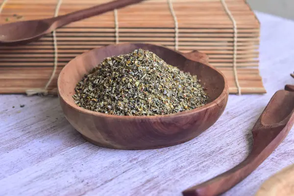 Fesleğen, İtalyan kurutulmuş ahşap kasede ahşap kaşıklarla bitkiler kesiyor. Açılı görünüm