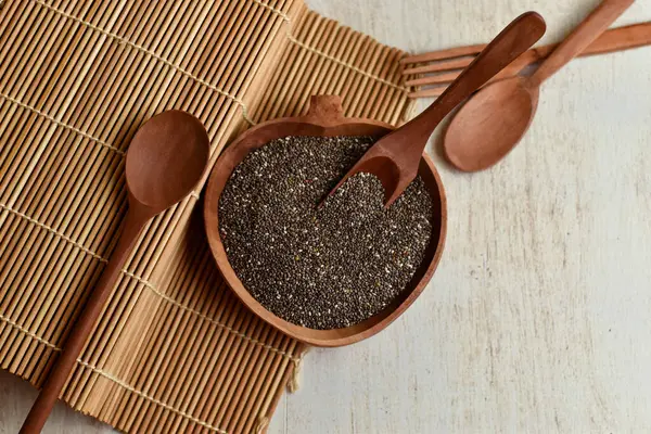Tahta kasede siyah chia tohumu yığını bambu suşi hasırının üstünde.