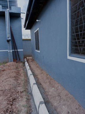 Evdeki kaldırımları döşüyorlar. Bir evin etrafında beton bloklar oluşturuluyor.