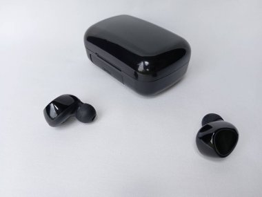 Siyah bluetooth kulaklıkları kapat ve beyaz arkaplanda izole edilmiş şarj dosyası.