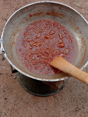 Kırmızı domates yahnisini büyük metal bir tencerede hazırlıyorum. Pişirirken çıkan buharla kaynatılmış domates yahnisi. Kaynar yağda ahşap spatulayla karıştırılıyor. Gıda süreci.