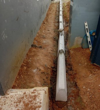 Evdeki kaldırımları döşüyorlar. Bir evin etrafında beton bloklar oluşturuluyor.