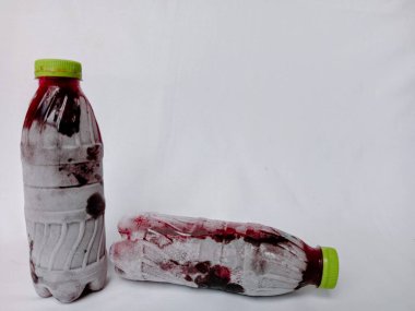 Beyaz arka planda donmuş amber yaprağı şişeleri. Ev yapımı şişelenmiş ve soğutulmuş sobolo içeceği şişenin etrafında buz ya da buz kristalleri var. Dondurulmuş amberçiçeği plastik şişede içer..