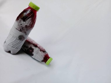 Beyaz arka planda donmuş amber yaprağı şişeleri. Ev yapımı şişelenmiş ve soğutulmuş sobolo içeceği şişenin etrafında buz ya da buz kristalleri var. Dondurulmuş amberçiçeği plastik şişede içer..