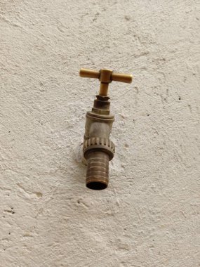 Su akmayan beyaz beton bir duvarda eski bir pirinç musluk. Dünya su günü.