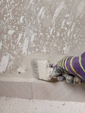 Boya fırçasıyla yeni bir beton duvar boyayan bir ressamın yakın görüntüsü. Boyama kavramı.