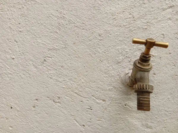 Su akmayan beyaz beton bir duvarda eski bir musluk ve yazı için yer. Dünya su günü.