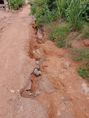 Kumasi, Gana - 29 Haziran 2025: Yerel halk Kumasi, Gana 'da kum ve kumlu yol yoğun yağışlardan etkilenerek şiddetli toprak erozyonuna neden oldu. Sokak, köydeki kötü tozlu tehlikeli yol. Uzak alan.