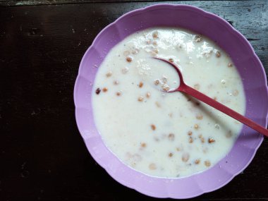 Gari 'nin kaşıkla mor kâseye batırılması. Gari, şeker, süt, yerfıstığı ya da fıstık ve suyun karışımından yapılan Ganalı tatlısı. Gari taze nişasta manyok köküdür. Batı Afrika 'da popülerdir..