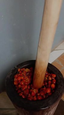 Tahta havan topu içindeki fındık manzarası. Tahta havan ve tokmak kullanarak avuç içi fındık ezmek. Gana palmiye fıstığı çorbası ve palmiye yağı yapma süreci.