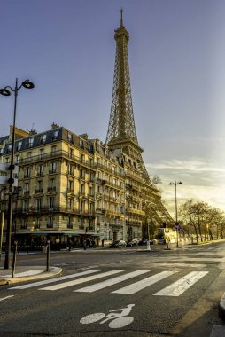 Paris, Fransa - 14 Ocak 2025: Sıcak bir ışık altında Haussmann binalarıyla dolu bir caddeden Eyfel Kulesi 'nin güzel manzarası