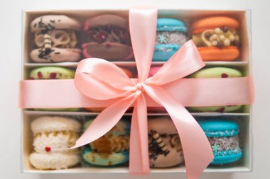 Sweet colorful macarons on white background. Tasty macaroons. Minimal food bakery concept. Sweet almond colorful pastel pink blue yellow green macaron. French macaroon cake. Macaroons in box.