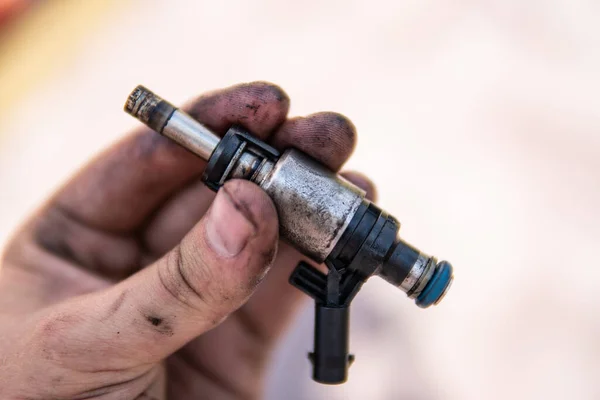 Dirty car injector in hands. Car repair concept. Increased fuel consumption. Car fuel system.