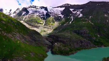 Karlı Tepeleri ve Yeşil Vadileri olan Engebeli Dağ Sıraları.