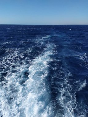 Kızıl Deniz 'e giden bir yattan görüntü. Yatın motorundan gelen dalgalar. Ufuk çizgisi gökyüzünü ve denizi birbirine bağlıyor.