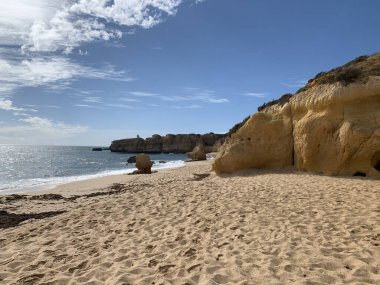 Kumlu ve taşlı plaj ve Portekiz 'in Algarve sahilinde mavi bir gökyüzü.