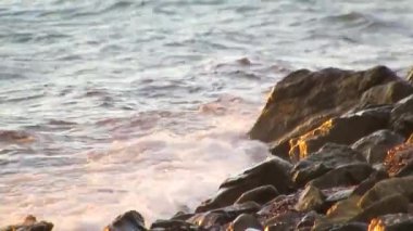 Gün batımında dalgalar kayalıklara çarpıyor.