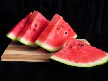 Karpuz, kesme tahtasındaki karpuz dilimleri, siyah arka plan.