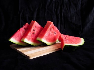 Karpuz, kesme tahtasındaki karpuz dilimleri, siyah arka plan.