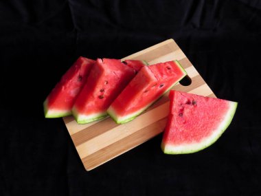 Karpuz, kesme tahtasındaki karpuz dilimleri, siyah arka plan.