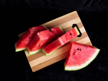 Karpuz, kesme tahtasındaki karpuz dilimleri, siyah arka plan.