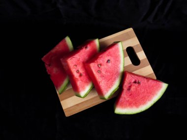 Karpuz, kesme tahtasındaki karpuz dilimleri, siyah arka plan.