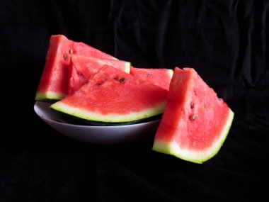 Karpuz, kesme tahtasındaki karpuz dilimleri, siyah arka plan.