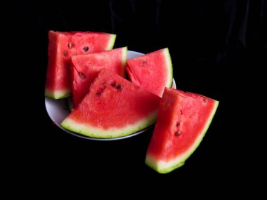 Karpuz, kesme tahtasındaki karpuz dilimleri, siyah arka plan.