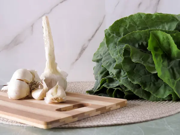 Sarımsaklı karanfil ve tahta kesme tahtasında taze salata.