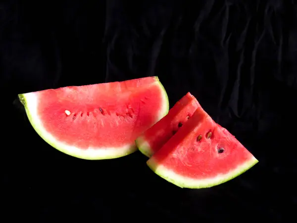 Karpuz, kesme tahtasındaki karpuz dilimleri, siyah arka plan.