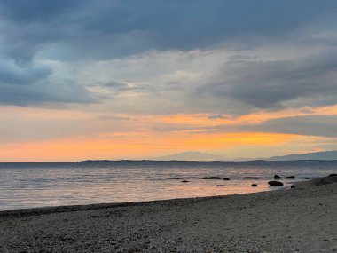 Denizin üzerinde gün batımı dalgalar kıyıya vuruyor.