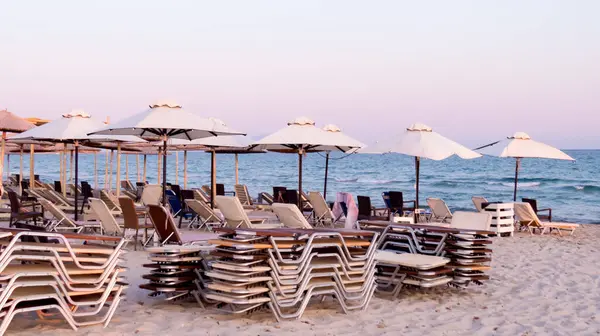 Akşamları kumsalda boş güneşlik ve şemsiyeler